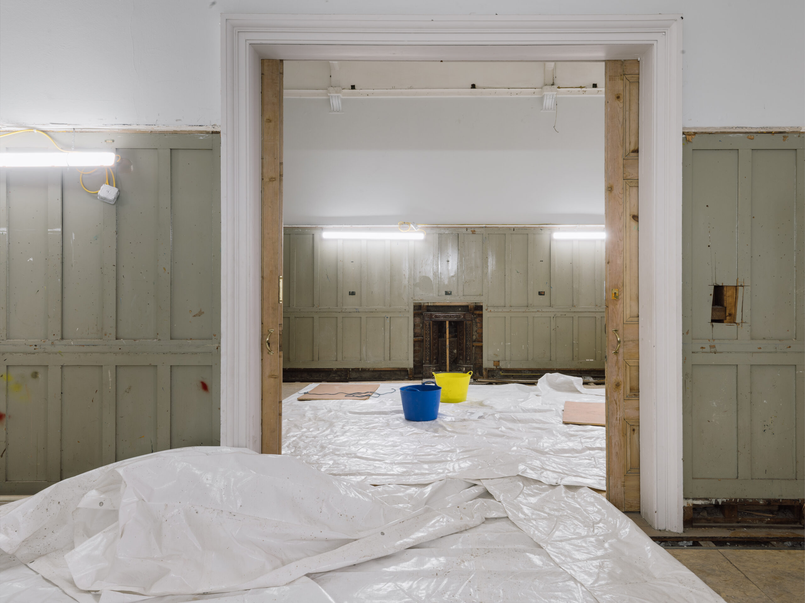 An empty gallery with plastic on the floor.