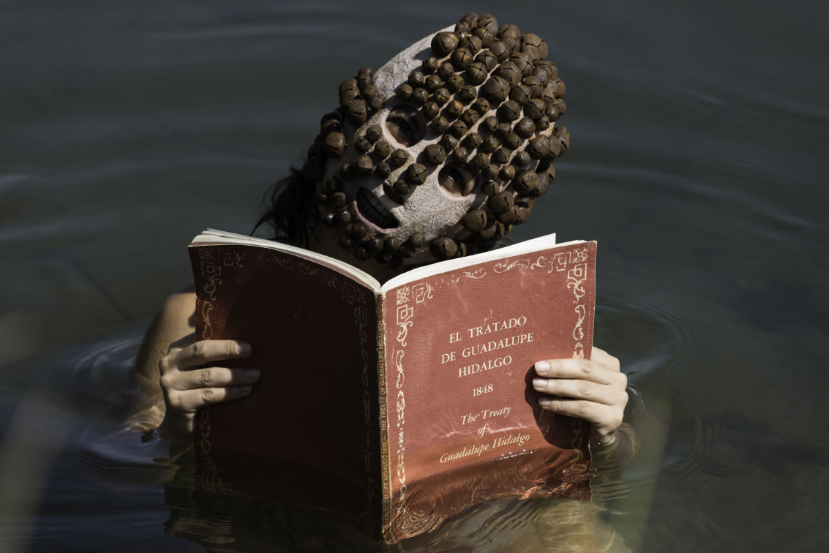A woman in a mask reading a book.